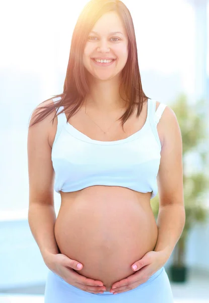 Primer plano de una mujer embarazada poniendo sus manos sobre su barriga . — Foto de Stock