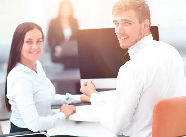 Mitglieder des Geschäftsteams sitzen am Schreibtisch und schauen in die Kamera . — Stockfoto