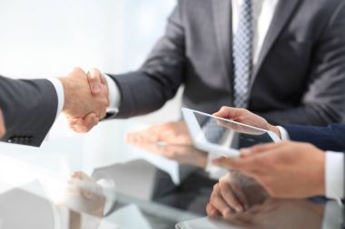 Bir toplantı sırasında el sıkışan iki emin iş adamları