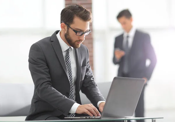 Hombre de negocios guapo está trabajando con el ordenador portátil en la oficina — Foto de Stock