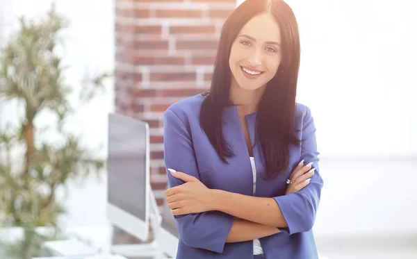 Aantrekkelijke jonge zakenvrouw staat in de buurt van een bureau in het kantoor — Stockfoto