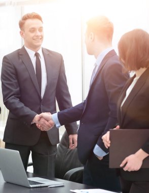 Ofisteki bir toplantıda iş ortakları tokalaşıyor.