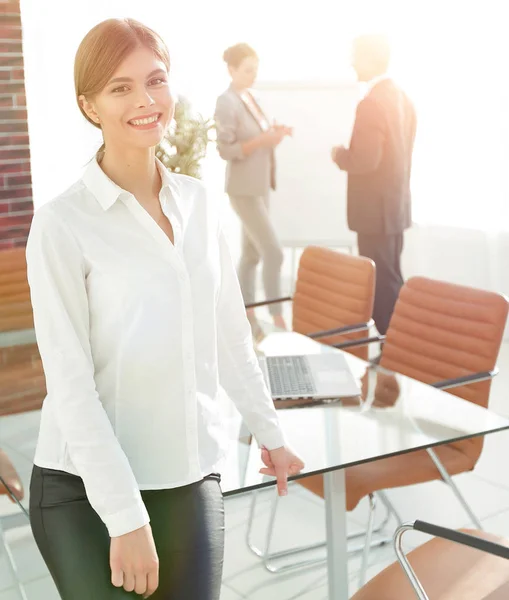 Junge Assistentin steht neben dem Schreibtisch. — Stockfoto