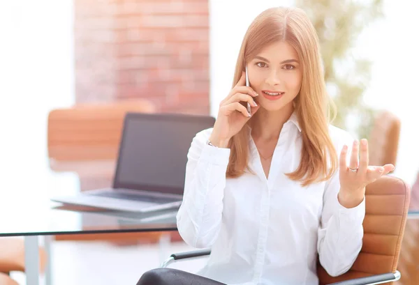 Bizneswoman rozmawia przez telefon komórkowy siedząc w biurze — Zdjęcie stockowe