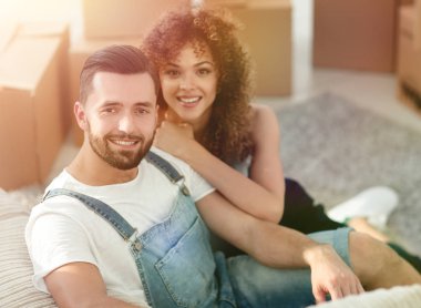 Genç bir çift yeni bir dairede yerde oturuyor.