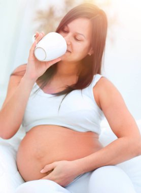 oturma odasında süt içme mutlu hamile kadın.