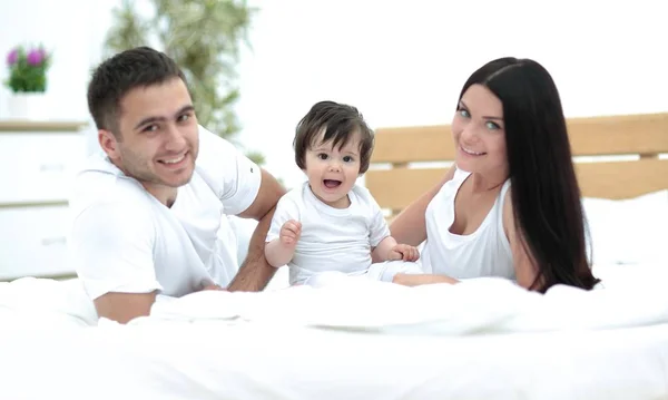 Una familia joven con niños pequeños a la cama en el dormitorio —  Fotos de Stock