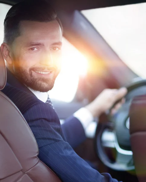 Businessman sitting at the wheel of a car and looking at the cam — Stock Photo, Image