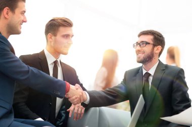 Ortaklar, takım üyelerinin huzurunda anlaşma yapıp el sıkışıyorlar.