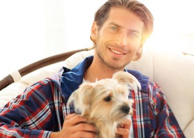 gülümseyen bir adam büyük bir koltukta otururken köpeğini okşayarak Close-Up.