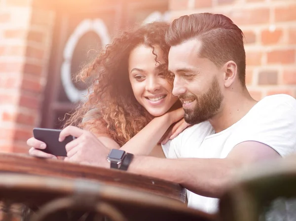 Feliz pareja amorosa usando un teléfono inteligente sentado en la terraza —  Fotos de Stock