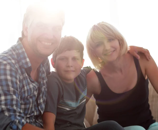 I genitori e il loro figlio si siedono rannicchiati nel soggiorno e sorridono — Foto Stock