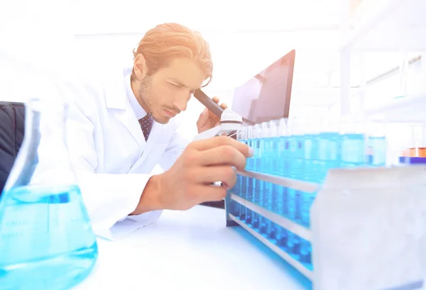 Químico mirando tubos de ensayo con líquidos azules — Foto de Stock