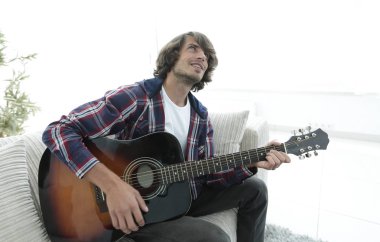 modern adam kanepede oturan gitar çalmak. bir yaşam tarzı kavramı