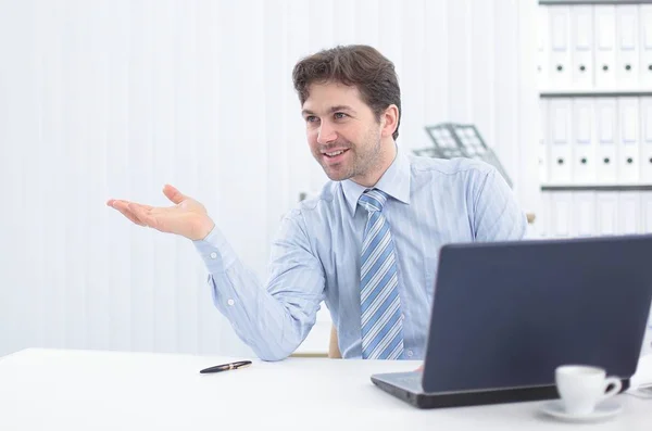Businessman sitting behind a Desk and pointing to copy space — Stock Photo, Image
