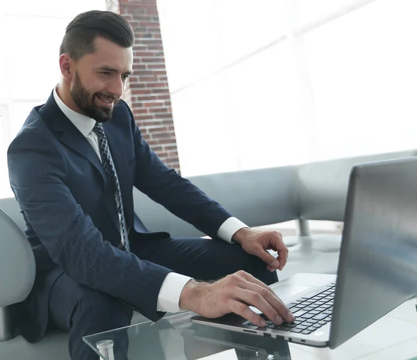 Hombre de negocios trabajando en portátil sentado en el vestíbulo de la oficina — Foto de Stock