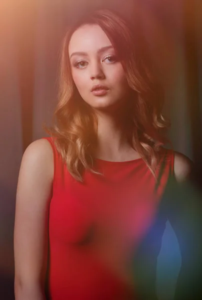 Morena encantadora em um vestido vermelho posando em um fundo preto . — Fotografia de Stock