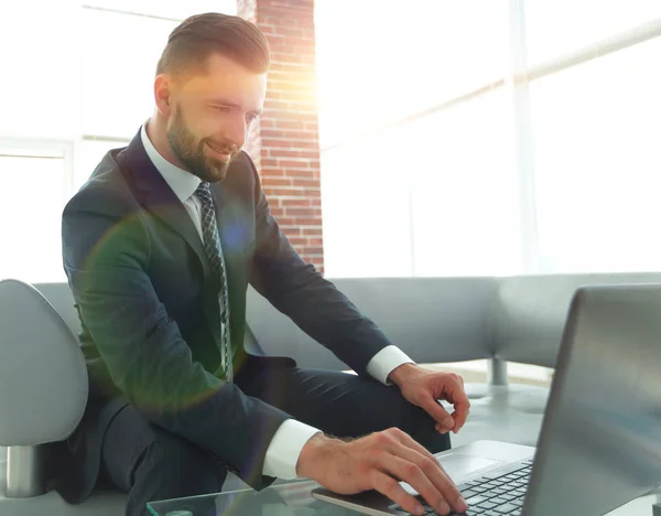 Homem de negócios trabalhando no laptop sentado no lobby do escritório — Fotografia de Stock