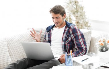 mutlu genç adam evden dizüstü bilgisayar ile çalışma.