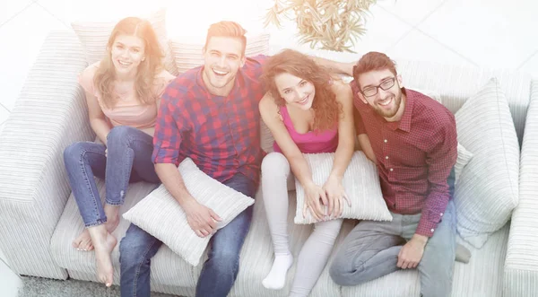 Fröhliche Gruppe von Freunden lacht, sitzt auf der Couch. — Stockfoto