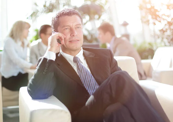Счастливый молодой бизнесмен, пользующийся сотовым телефоном в лобби отеля — стоковое фото