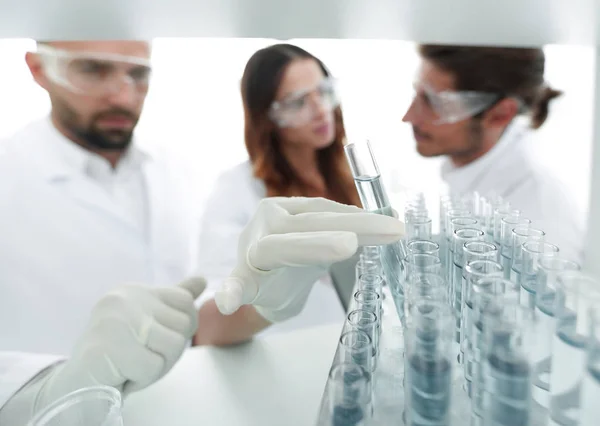 Immagine di sfondo è un gruppo di scienziati che studiano il liquido nel tubo di vetro . — Foto Stock