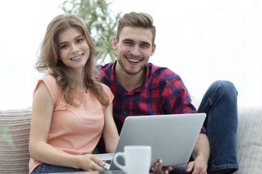 Genç çift çalisarak koltukta oturan laptop