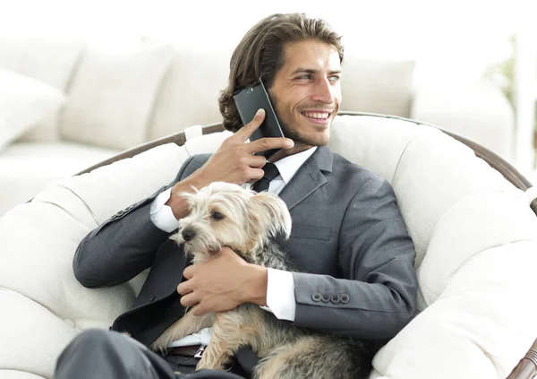 successful businessman holds his dog and pet and talks on the smartphone