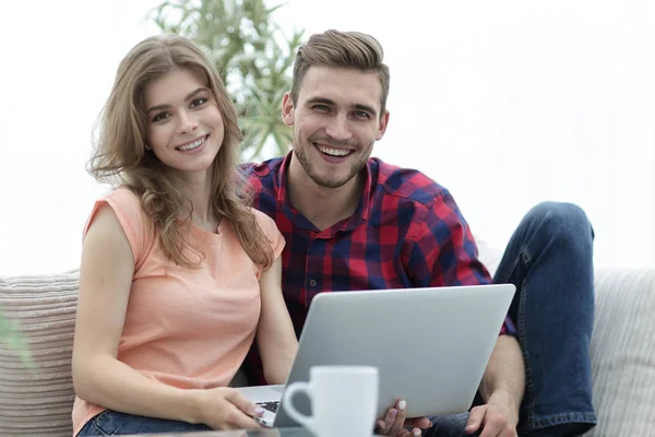 Jovem casal .working no laptop sentado no sofá — Fotografia de Stock