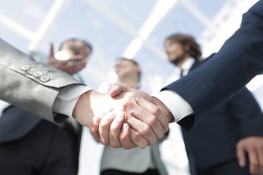 İş ortaklarının el sıkışması ön planda.