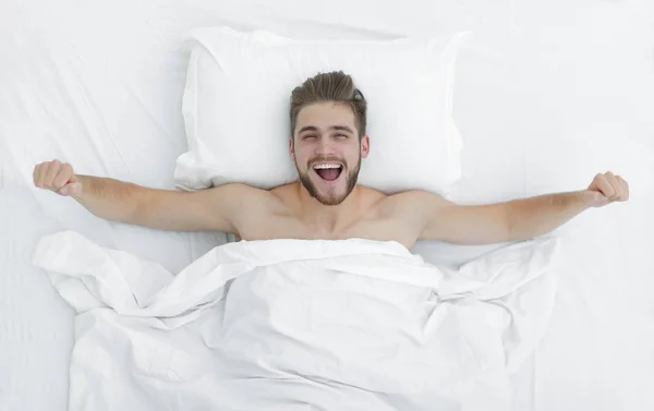 Bovenaanzicht. gelukkig man wakker worden in een comfortabel bed — Stockfoto