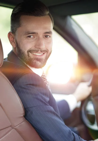 Bonito jovem sentado no banco da frente de um carro olhando para a câmera — Fotografia de Stock