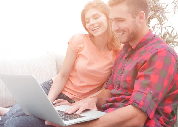 Uśmiechnięta Młoda para z laptopa siedząc na kanapie — Zdjęcie stockowe