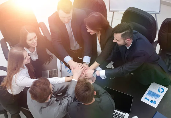 Equipo de negocios con las manos juntas en el escritorio — Foto de Stock