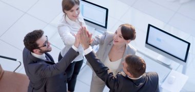 Başarılı bir iş ekibi ofiste birbirlerine beşlik çakıyor.