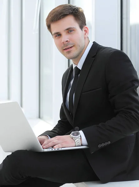 Jeune professionnel avec ordinateur portable sur fond de fenêtre de bureau — Photo