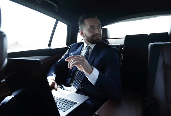 Podnikatel, sedí na zadním sedadle v autě a ukazoval jeho — Stock fotografie