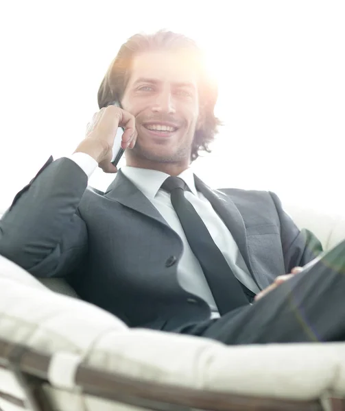 Hombre de negocios hablando en un teléfono inteligente mientras está sentado en una comodidad — Foto de Stock