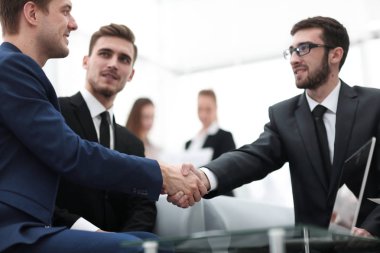 Ortaklar, takım üyelerinin huzurunda anlaşma yapıp el sıkışıyorlar.