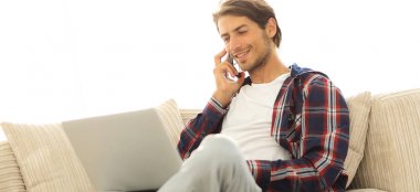 cep telefonu üzerinde konuşurken laptop ile ciddi genç adam