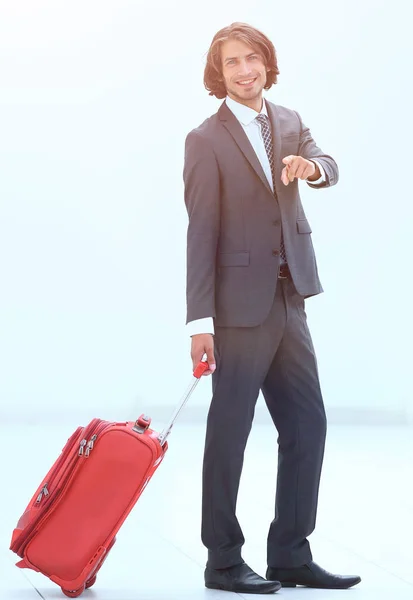 Homem de negócios com mala de viagem apontando para a frente — Fotografia de Stock