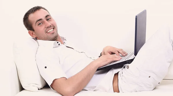 Человек работает на ноутбуке, сидит на диване — стоковое фото