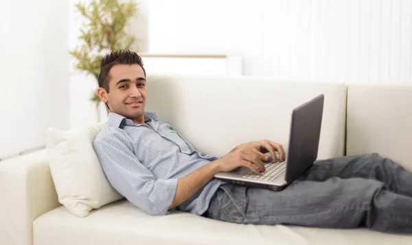 Facet z laptopa leżąc na kanapie — Zdjęcie stockowe