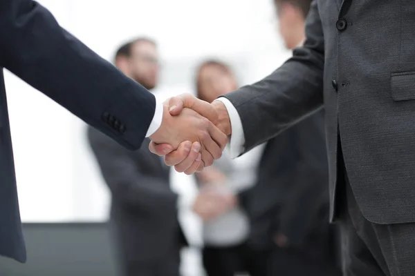 Két üzletember kezet fog kollégáival a háttérben.. — Stock Fotó
