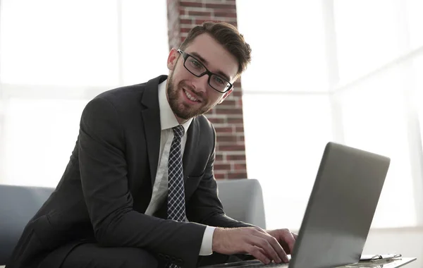 Jovem empresário usando laptop e sorrindo — Fotografia de Stock