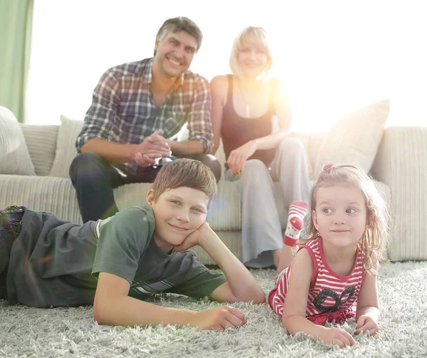 Portrét dětí, zatímco rodiče sedí na pohovce v obývacím roo — Stock fotografie