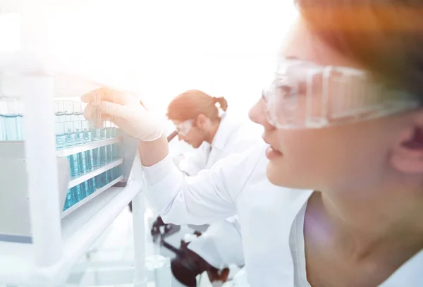 Mujer joven con tubos de ensayo en el laboratorio — Foto de Stock