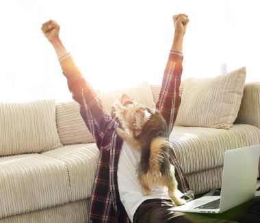 geniş bir oturma odasında otururken köpeğiyle mutlu adam