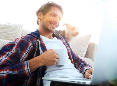 genç adam kanepede yakın katta oturan çay içiyor.