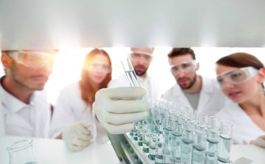 arka plan görüntüsü sıvı cam tüp içinde eğitim microbiologists oluşan bir gruptur.